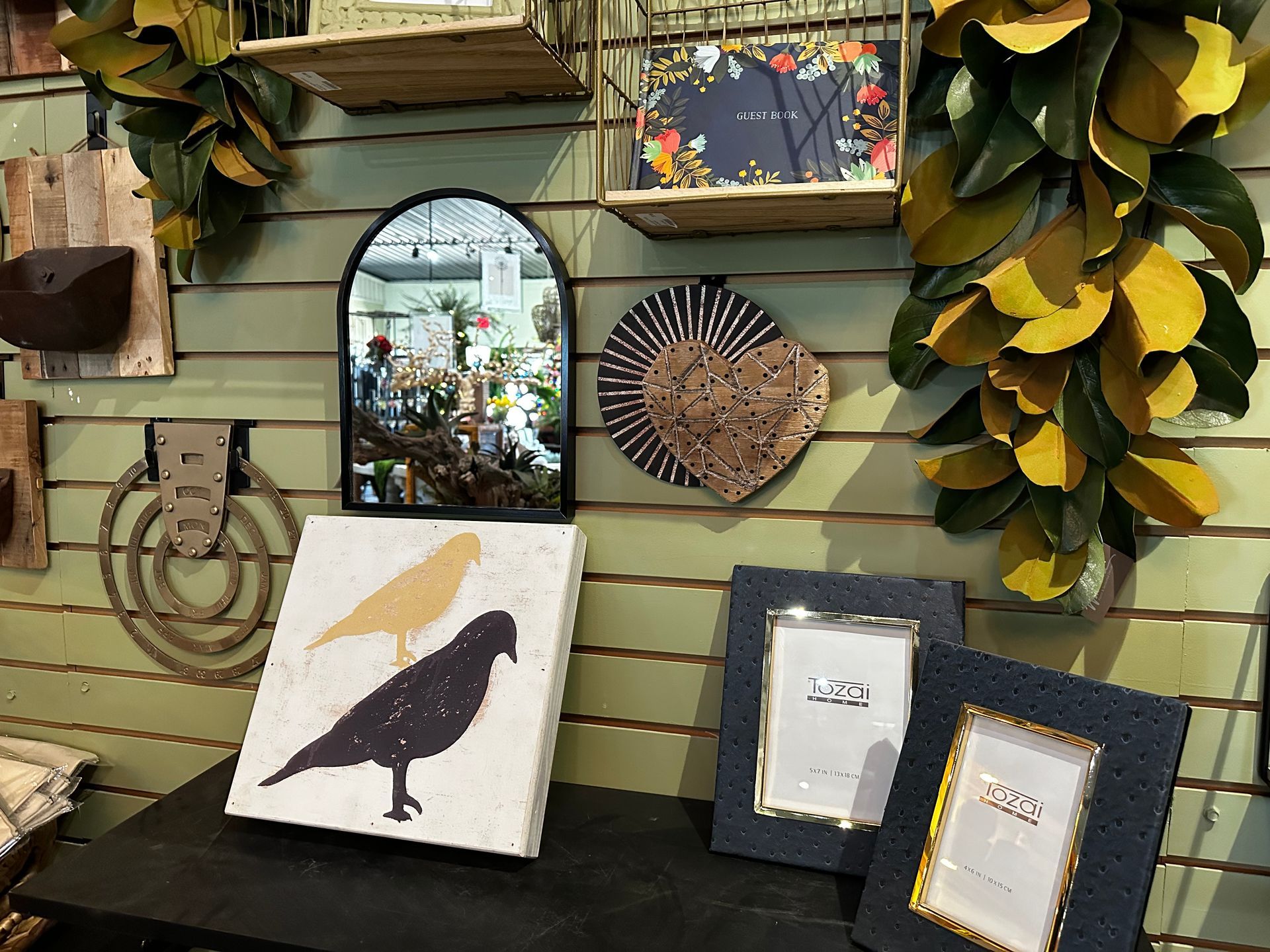 A painting of a bird is on a table in front of a wall.