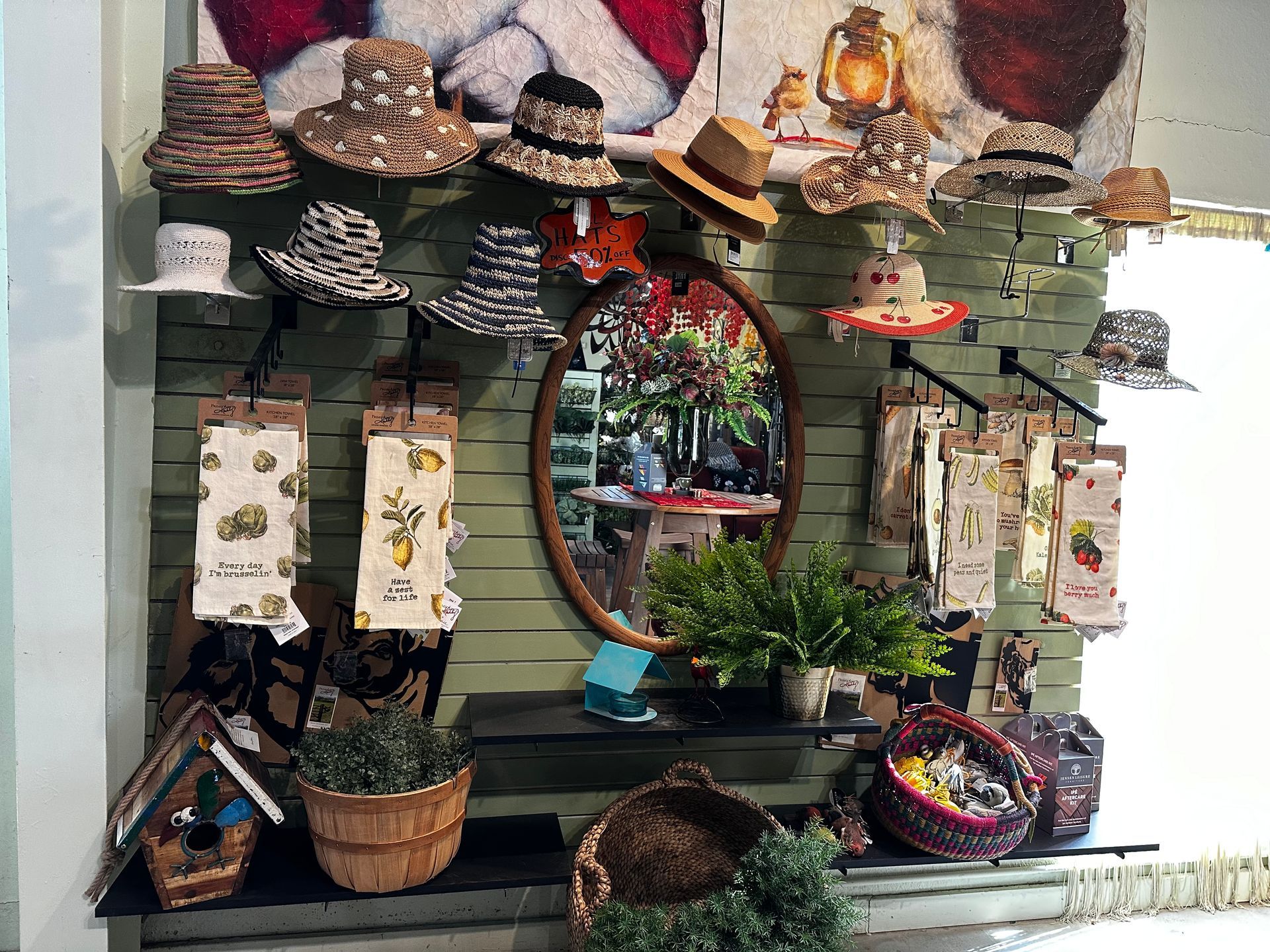A display of hats and baskets in a store with a picture of santa on the wall.