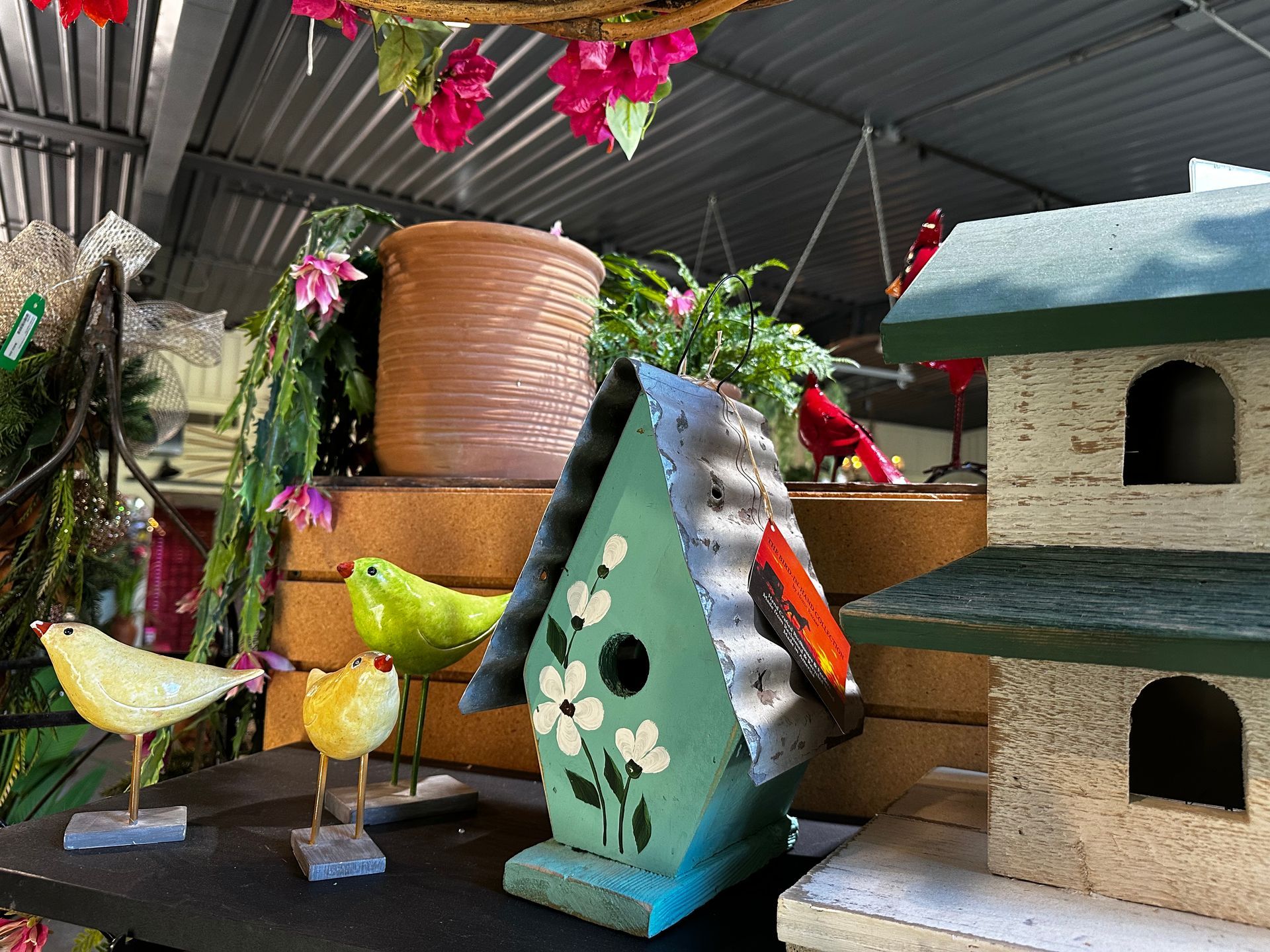 A birdhouse is sitting on top of a table next to a bird statue.