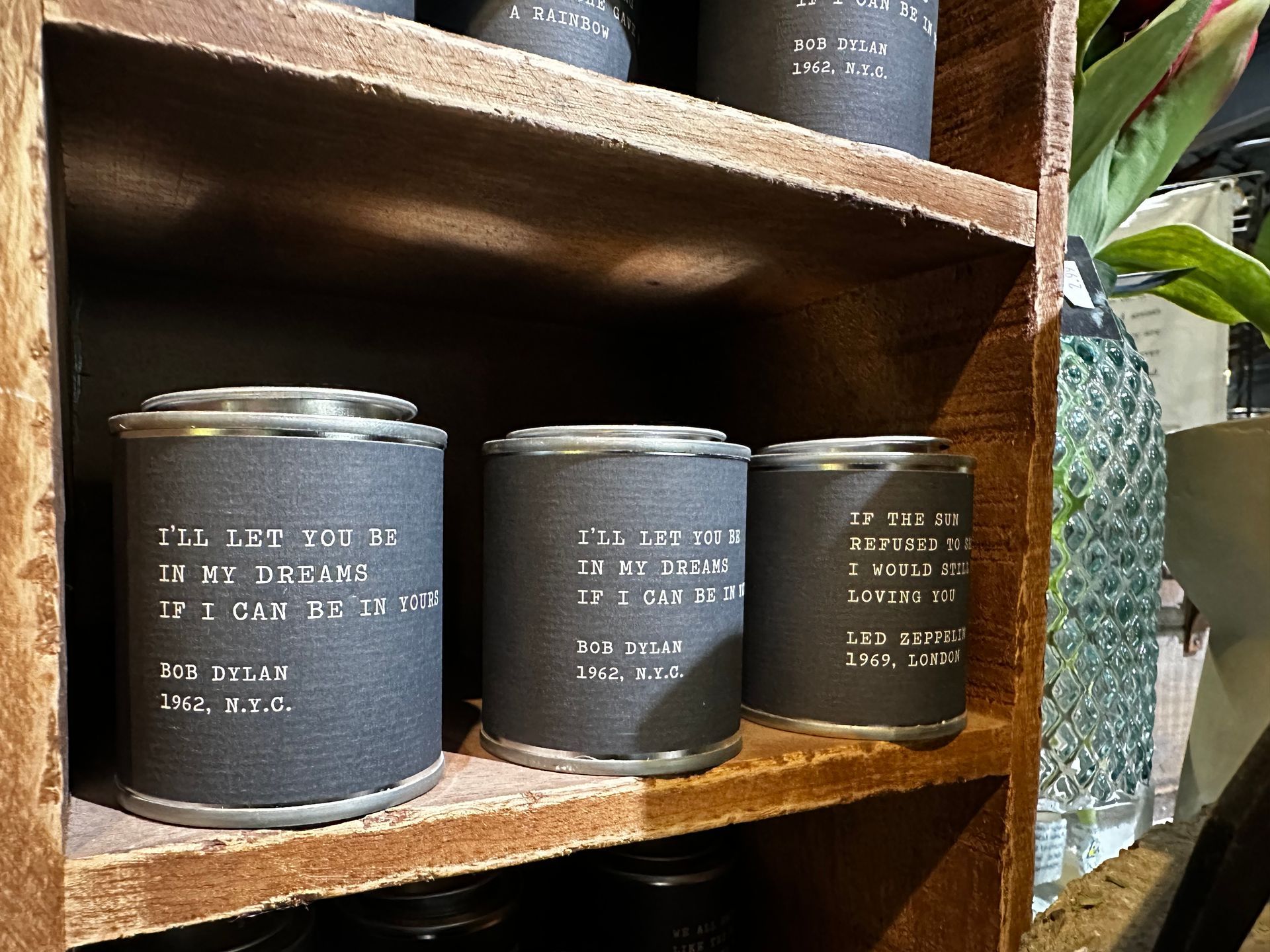 Three cans are sitting on a wooden shelf.