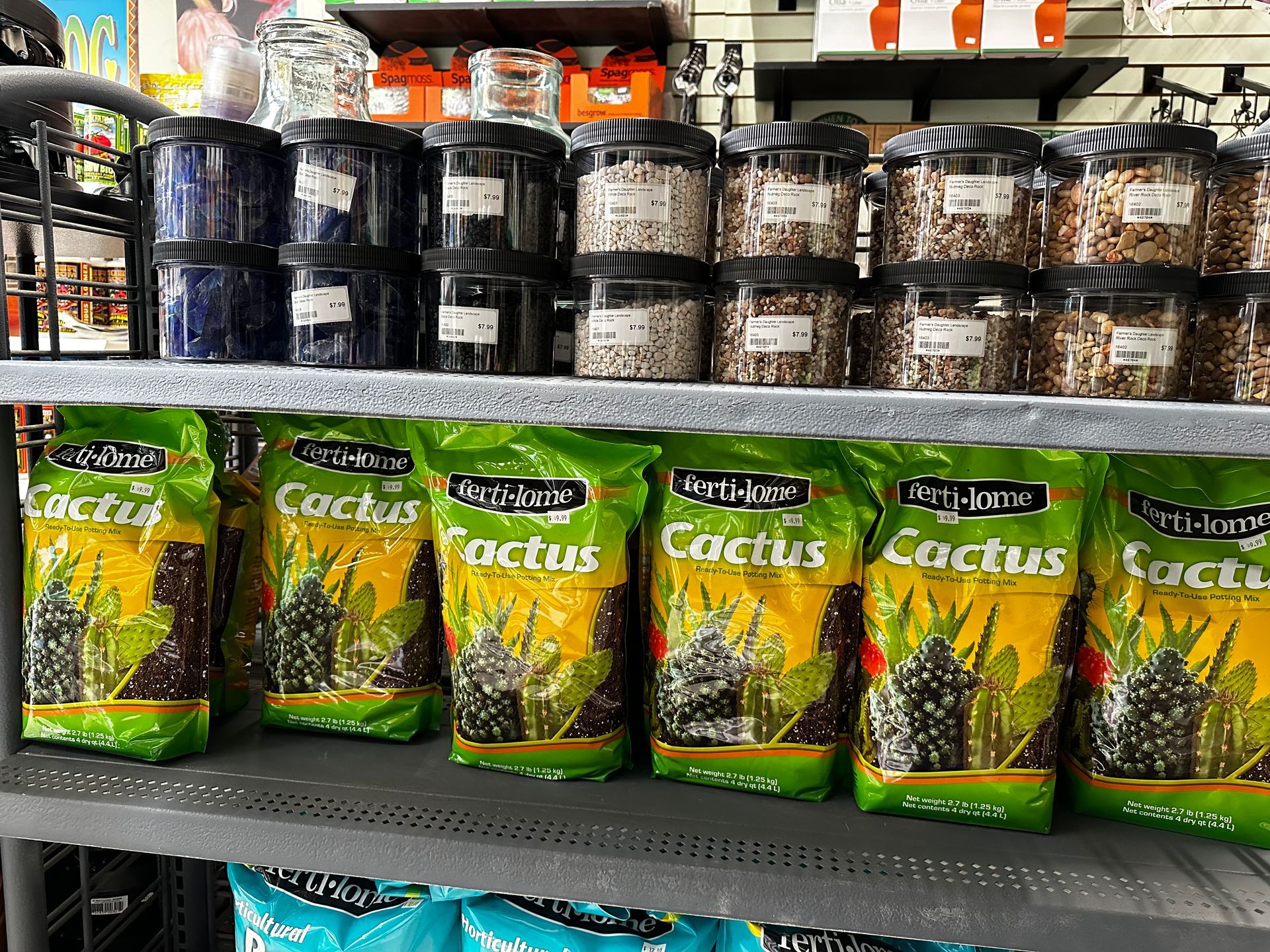 A shelf filled with bags of cactus soil and jars of cactus seeds.