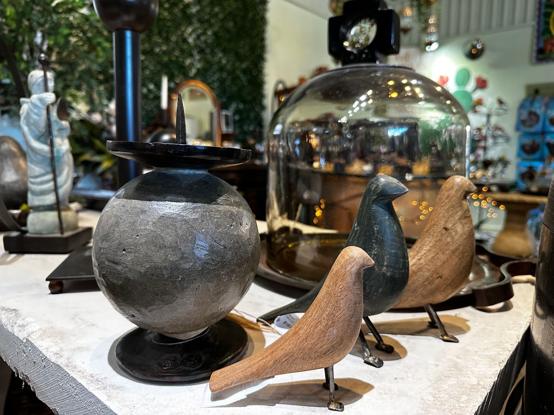 Two birds are sitting on a table next to a glass dome.