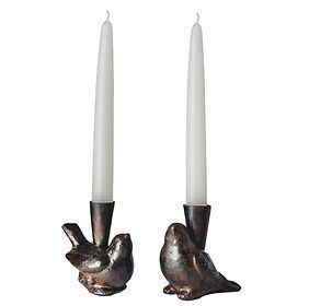 A pair of candle holders in the shape of birds with candles in them.