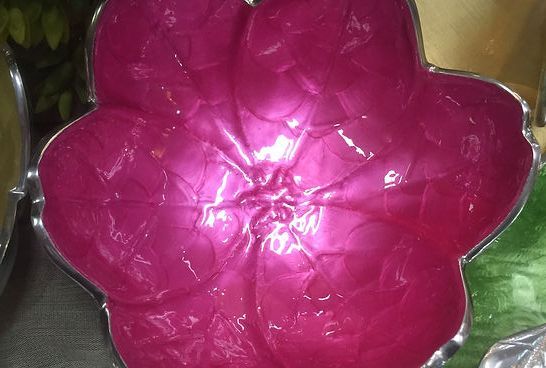 A pink flower shaped bowl is sitting on a table.