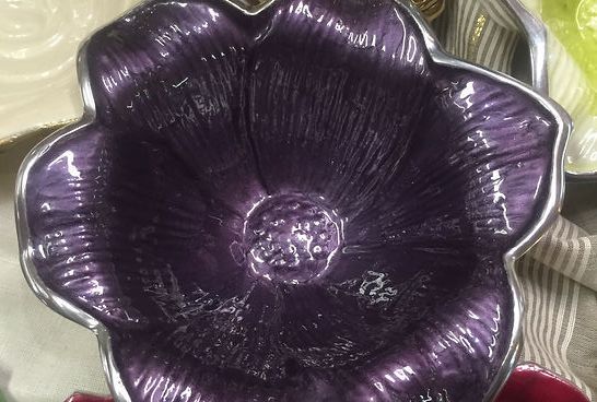 A purple bowl with a silver rim is sitting on a table.