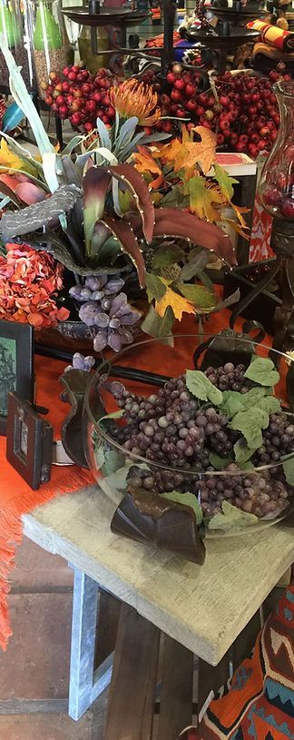 A table topped with a bowl of grapes and flowers.