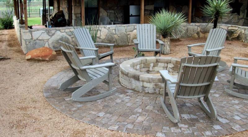 A group of rocking chairs are sitting around a fire pit.