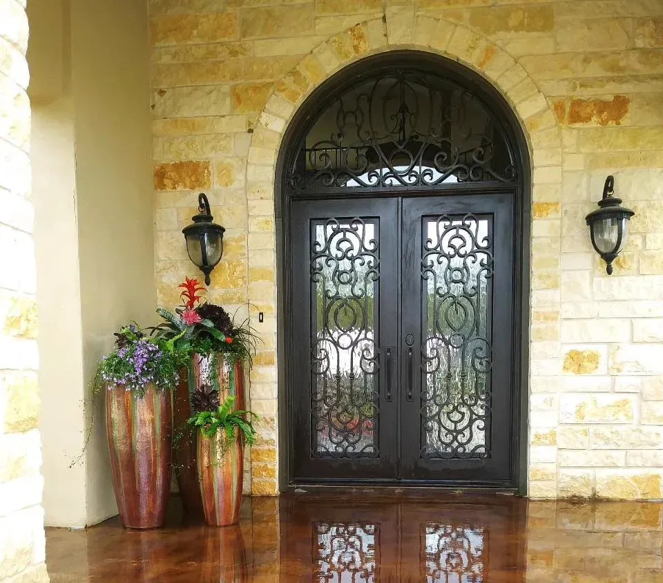 Two potted plants are in front of a wrought iron door