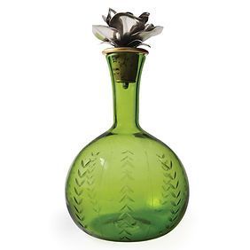 A green glass bottle with a flower on top of it.