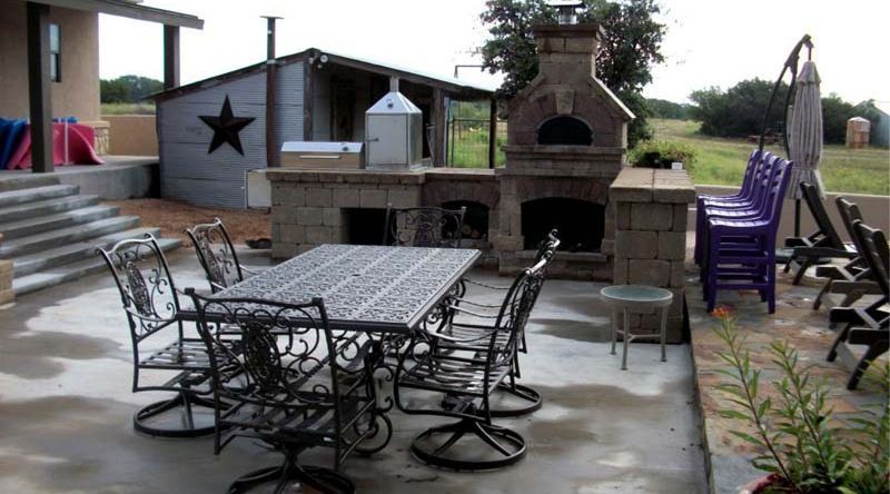 A patio with a table and chairs and a fireplace