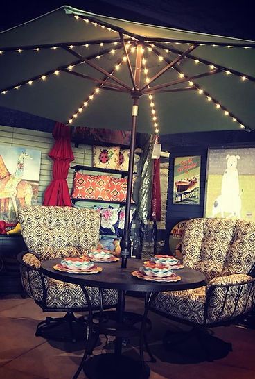 A patio with a table and chairs under an umbrella at night.