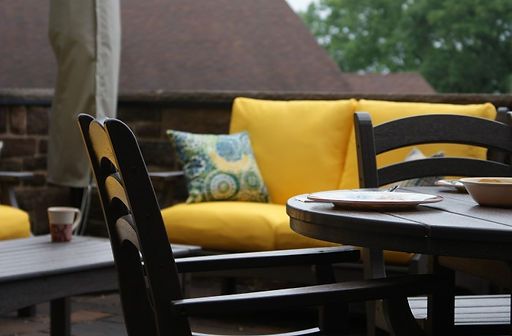 A patio with a table and chairs with yellow cushions