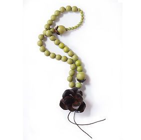 A necklace with green beads and a brown flower on a white background.