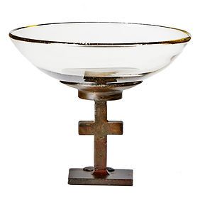 A glass bowl with a metal cross on top of it.