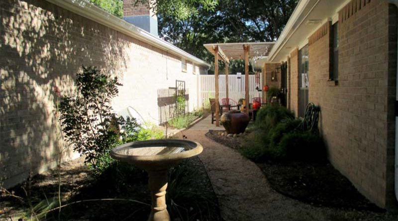 A brick house with a walkway leading to the backyard.