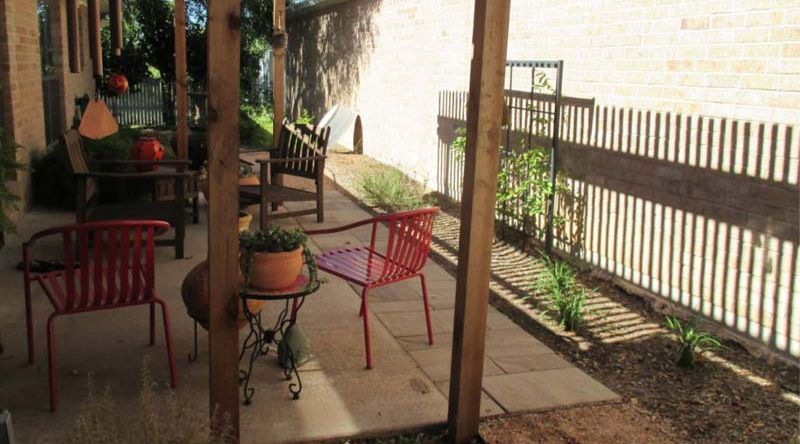 A patio with chairs and a table under a pergola.