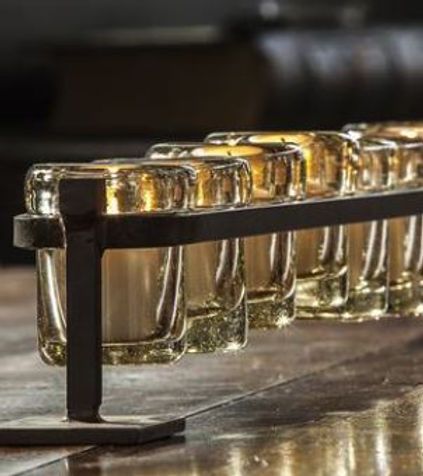A row of shot glasses sitting on top of a wooden table.