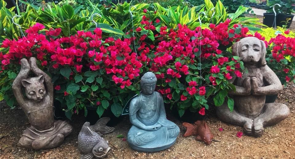 A group of statues sitting in front of a bush of flowers.