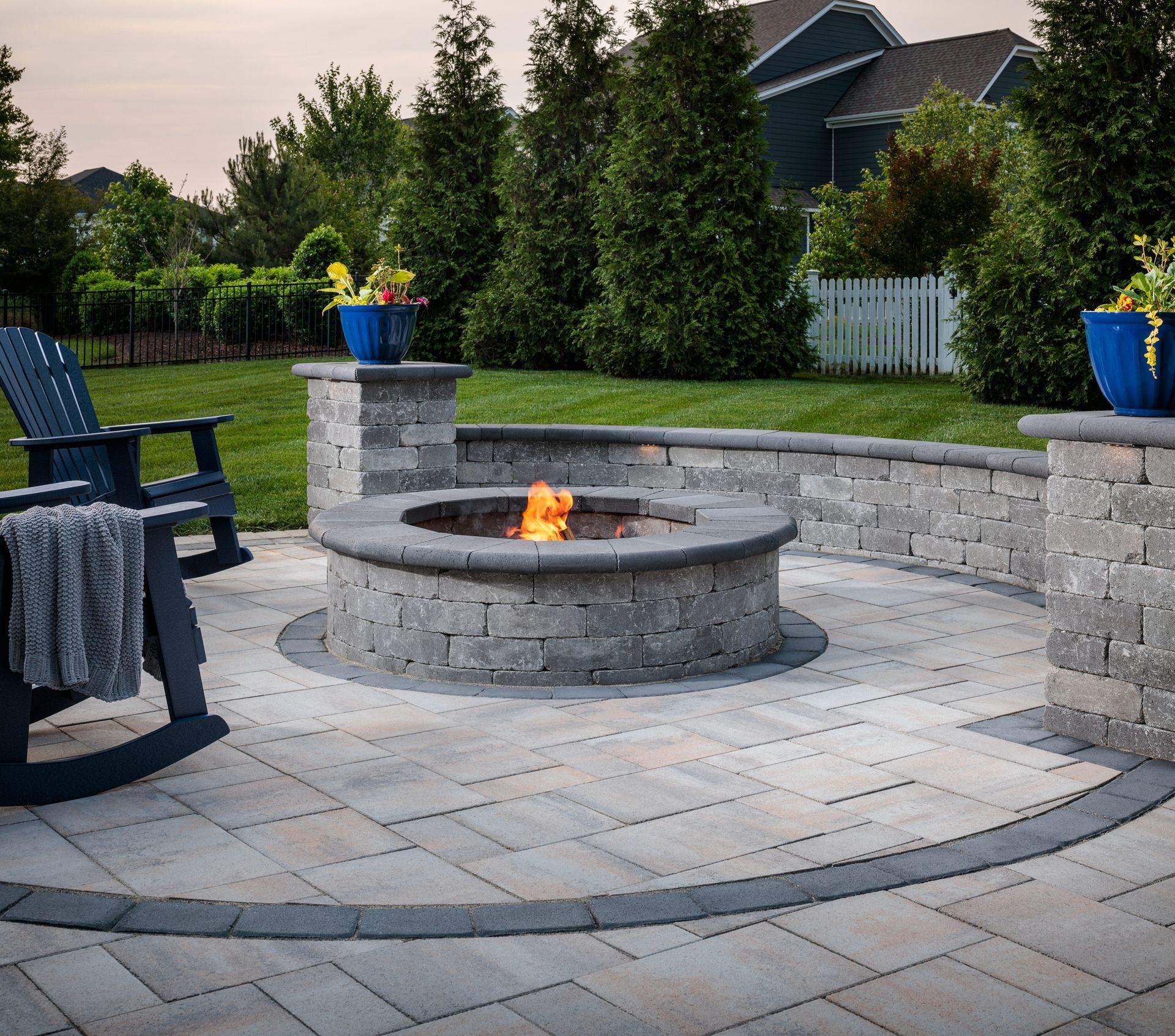 A rocking chair sits next to a fire pit on a patio