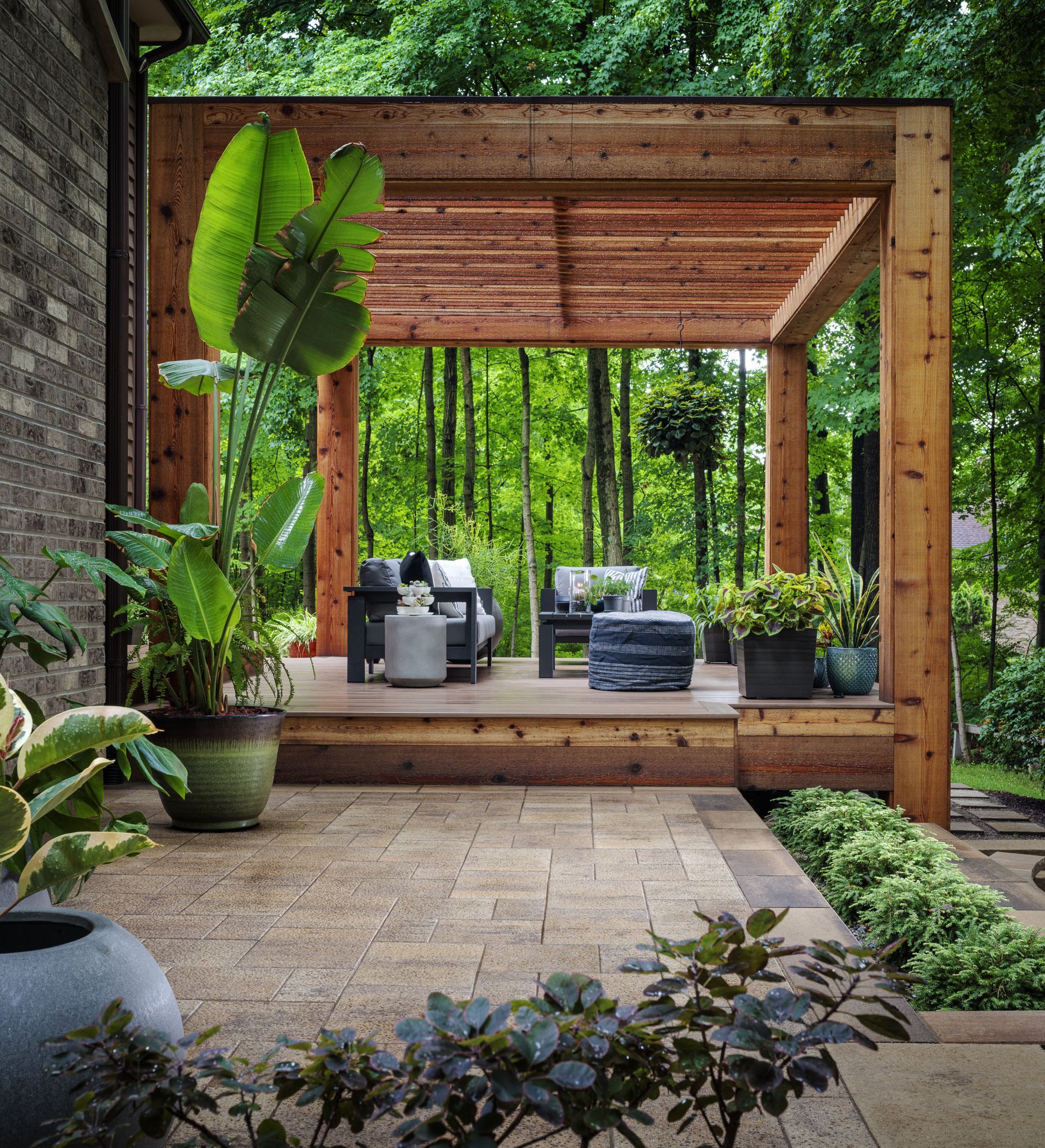 A patio with a wooden pergola and chairs and plants