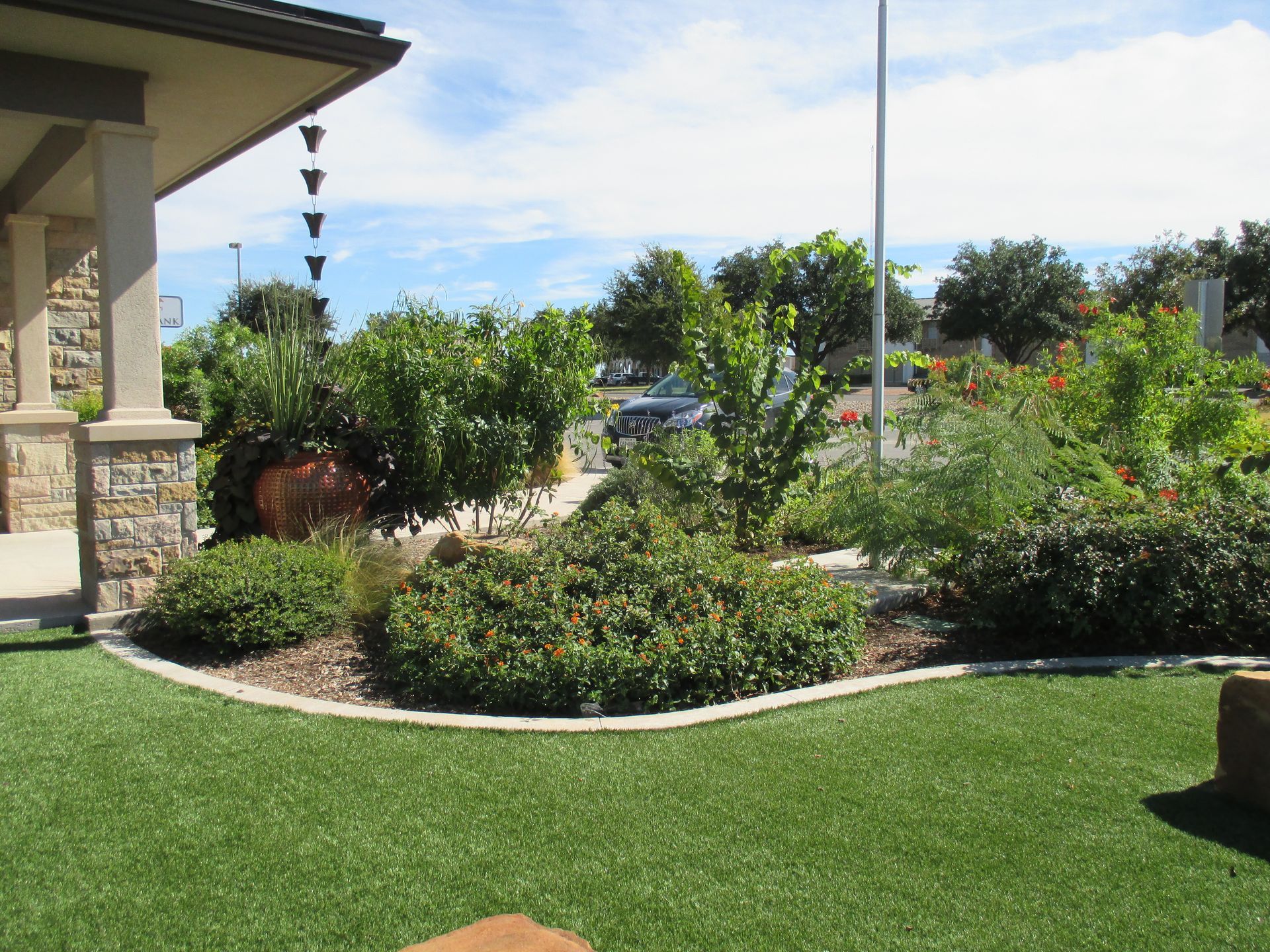 A dog is sitting on a lush green lawn in front of a house