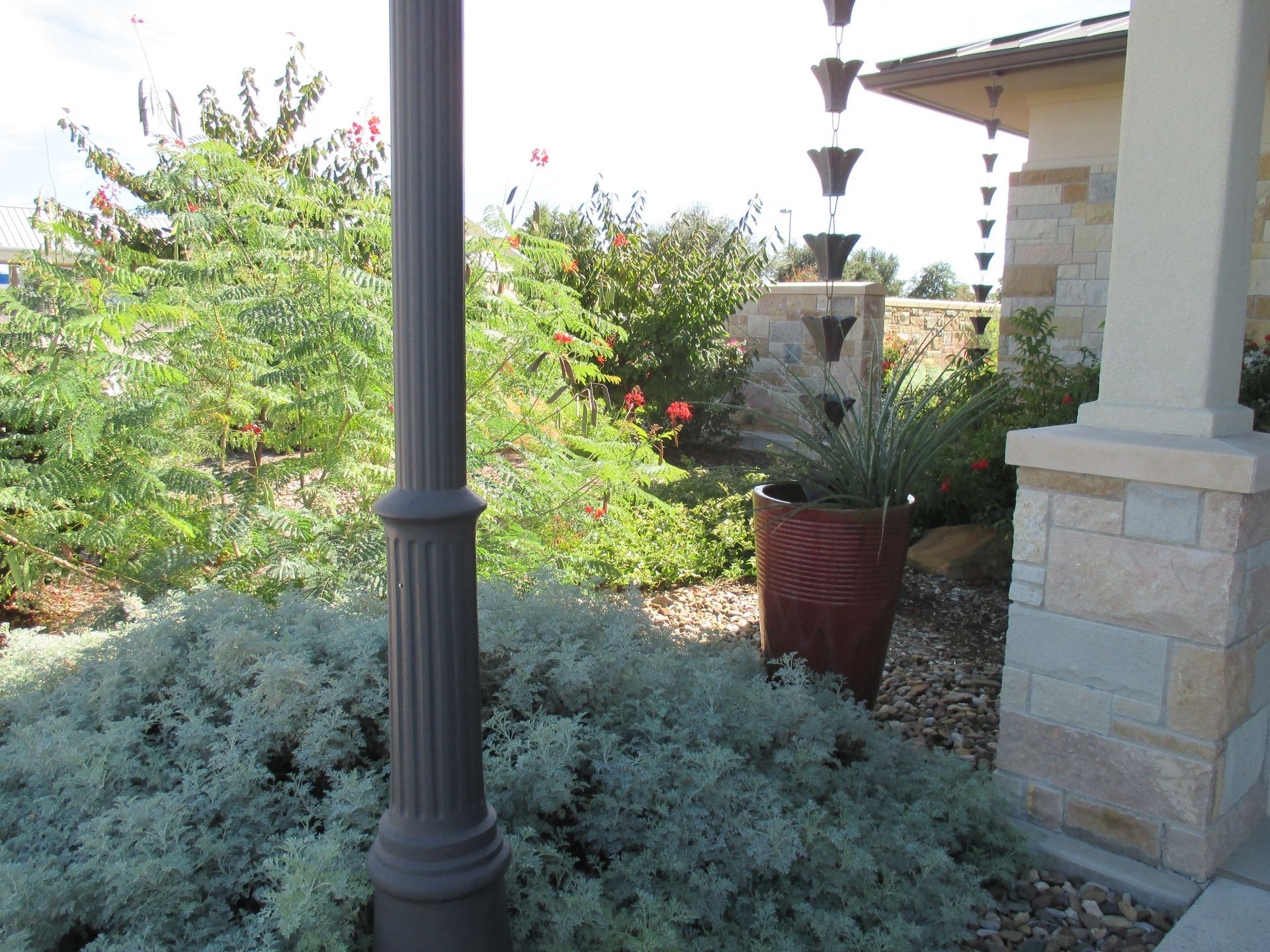 A potted plant sits next to a pole in front of a house