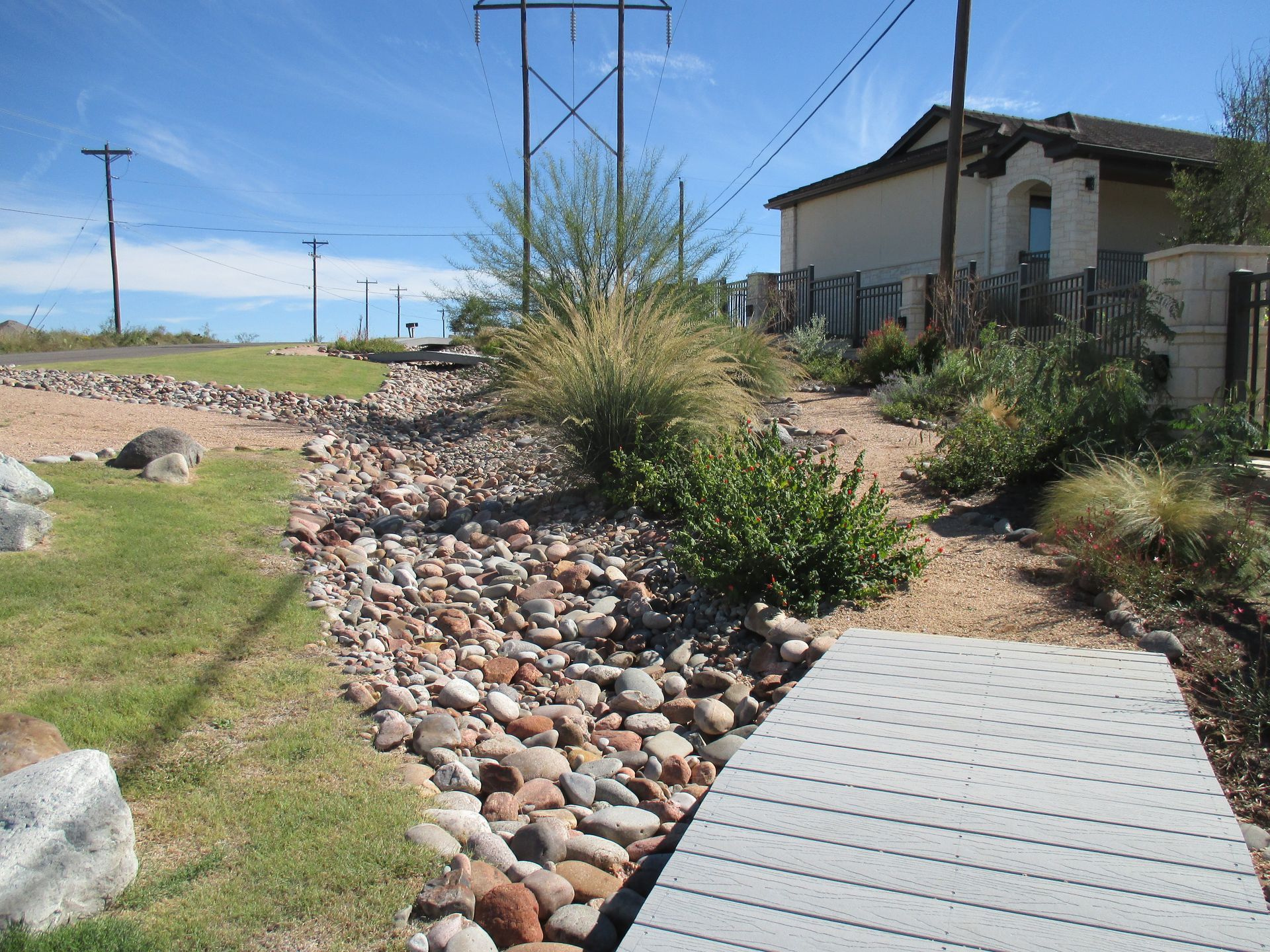 A concrete walkway surrounded by rocks and grass with a house in the background