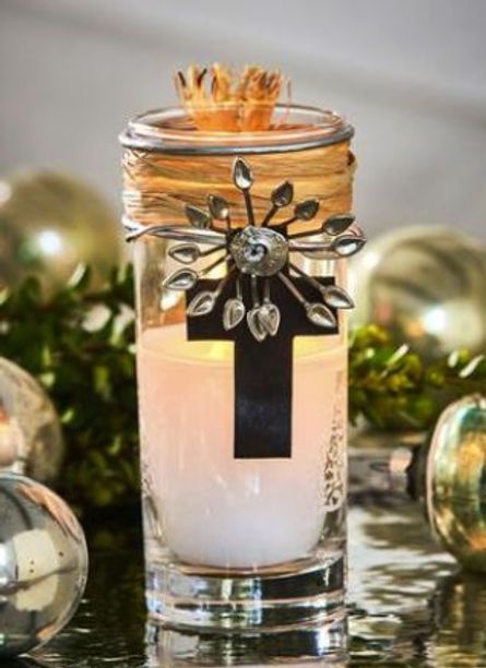 A candle in a glass with a cross on top