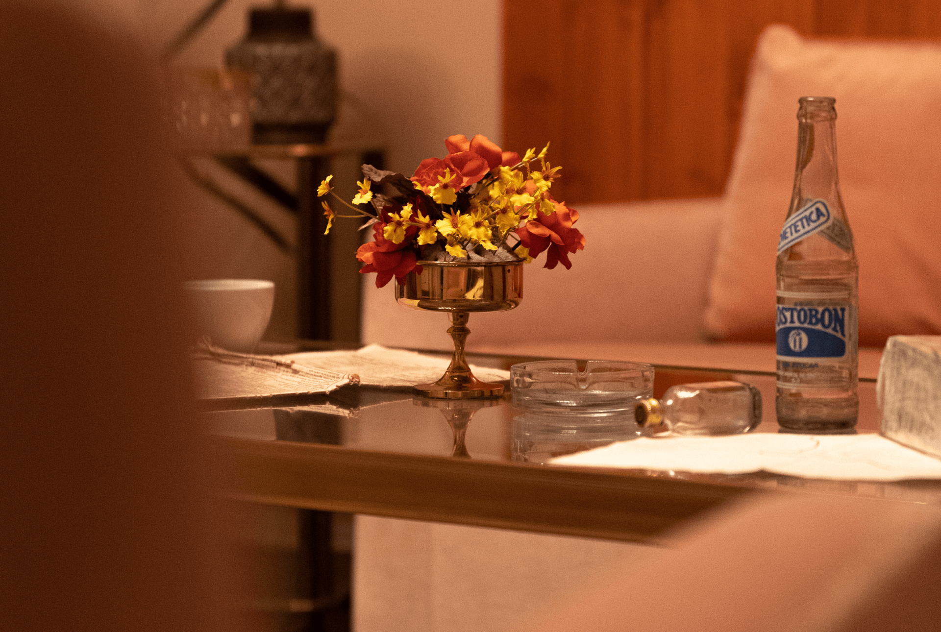 Ein Tisch mit einer Blumenvase und einer Flasche Wasser darauf.