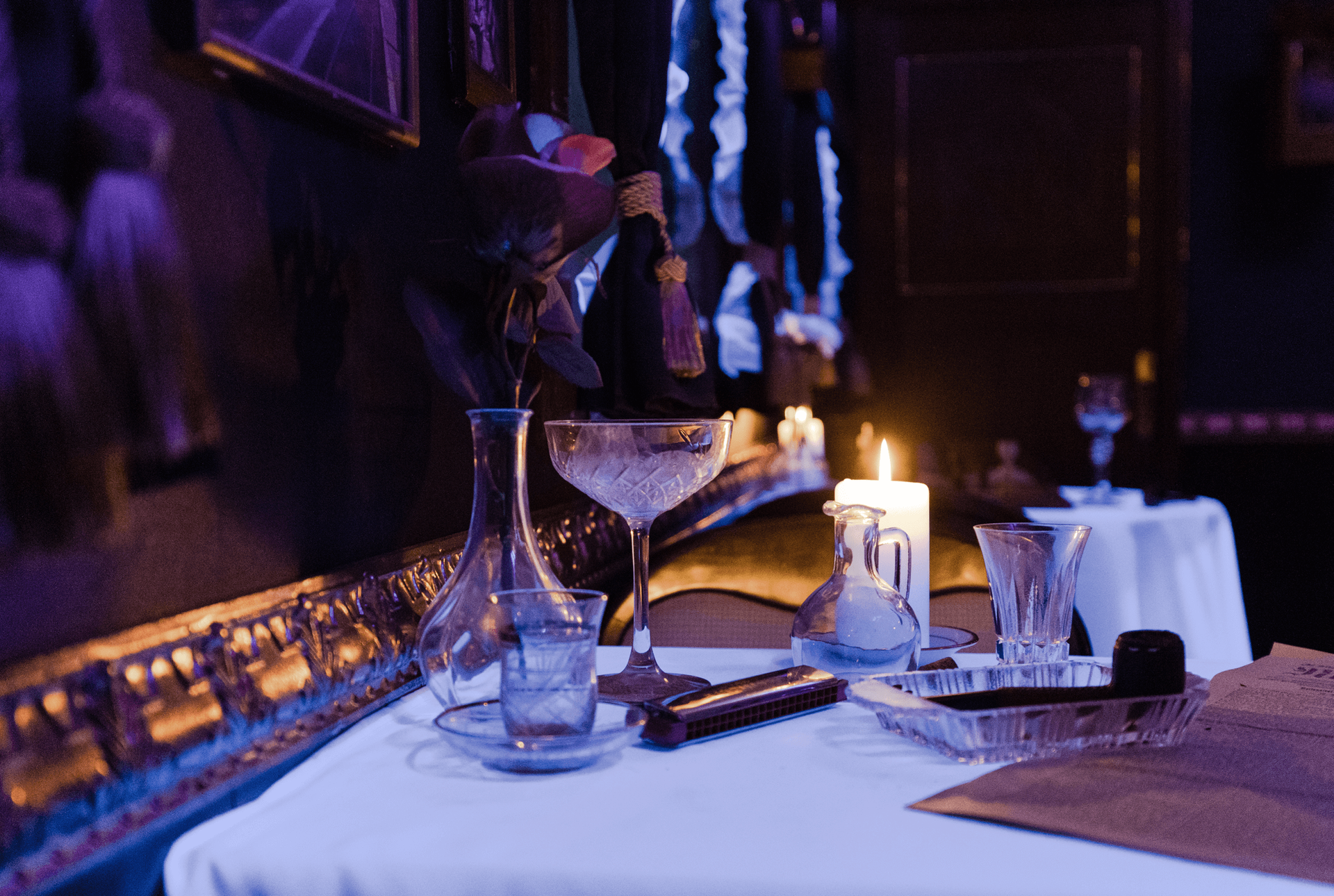 Ein Tisch mit einem Martini-Glas und einer Kerze darauf in einem dunklen Raum.