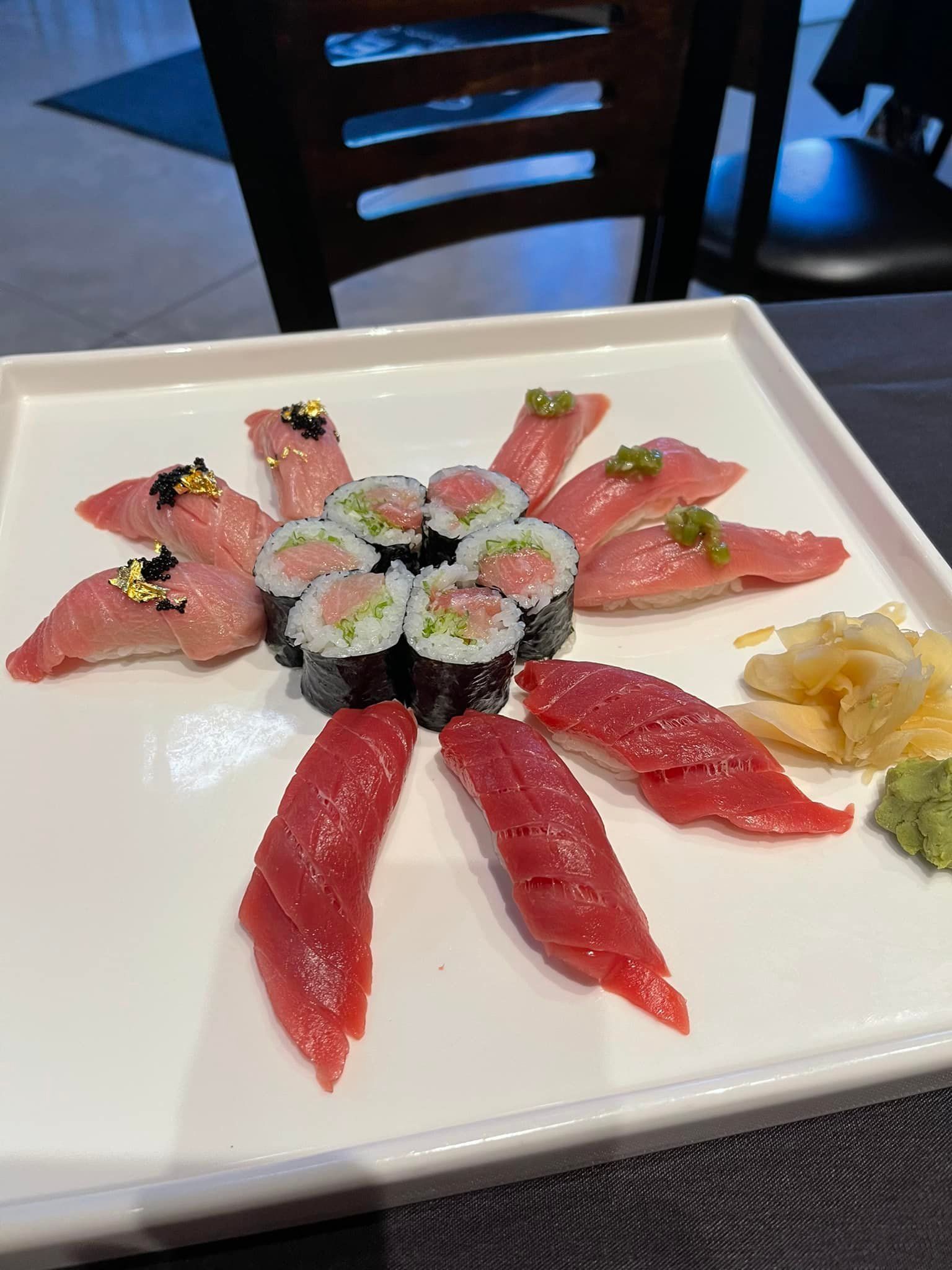 Sushi platter: tuna nigiri and rolls, arranged on a white square plate, with ginger and wasabi.