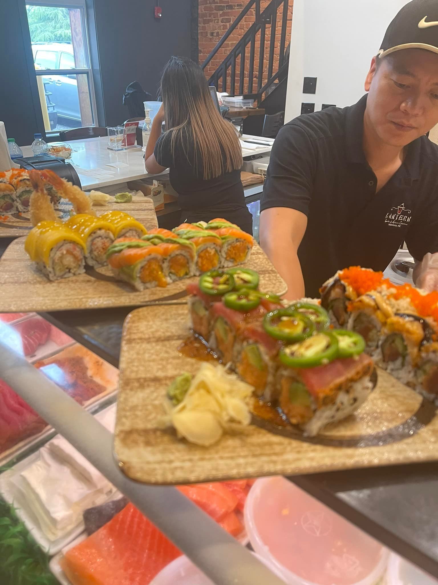 Sushi chef arranging colorful sushi rolls on display. Restaurant setting.