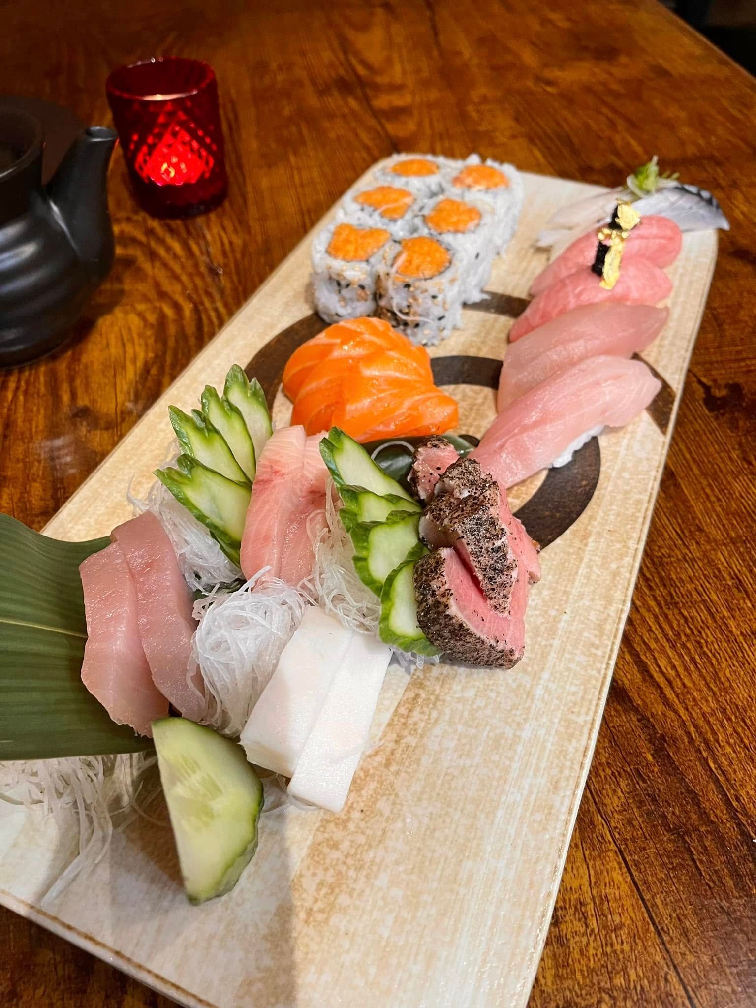 Sushi platter with various nigiri, sashimi, and rolls, on a wooden board.