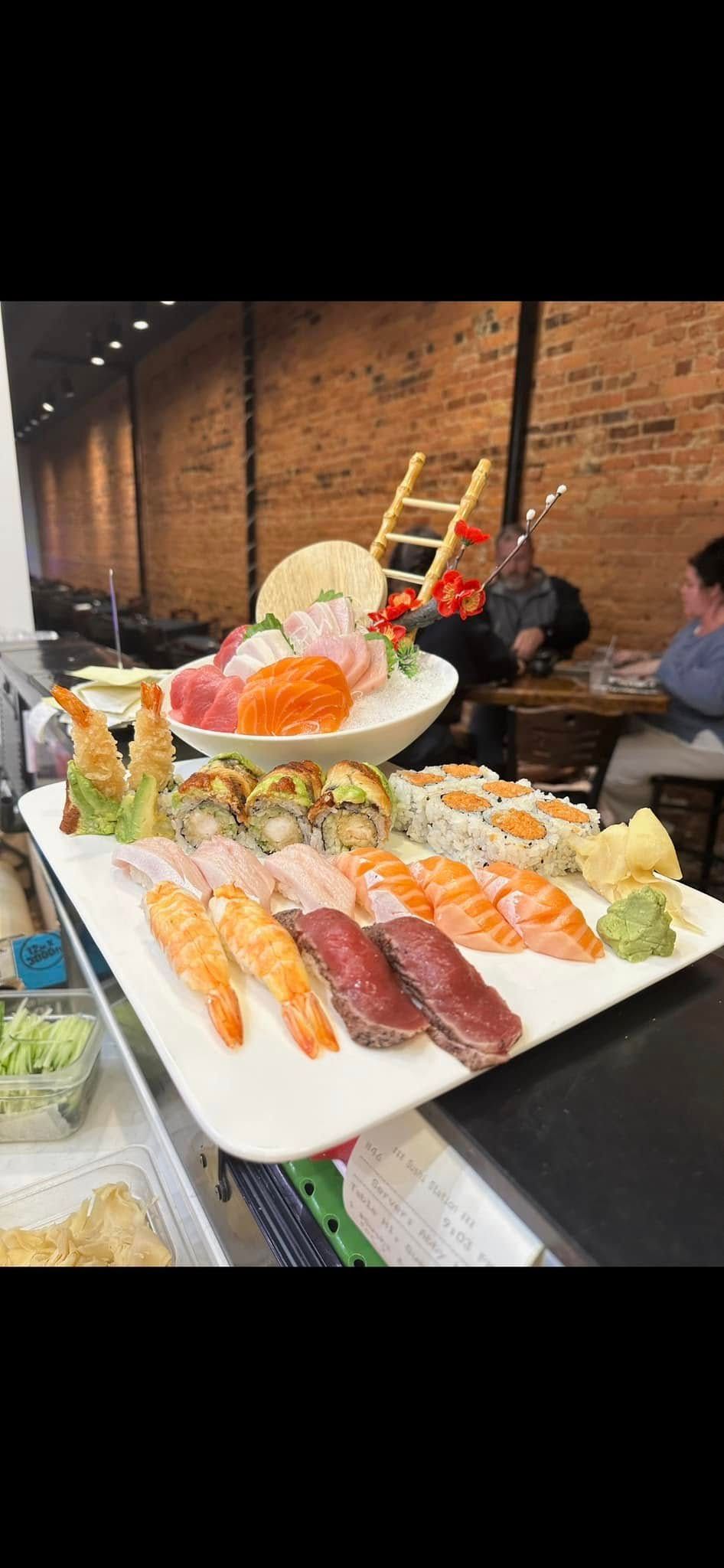 Sushi platter with various rolls, nigiri, and sashimi, set in a restaurant.