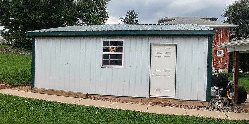 A white shed with a green roof and a window