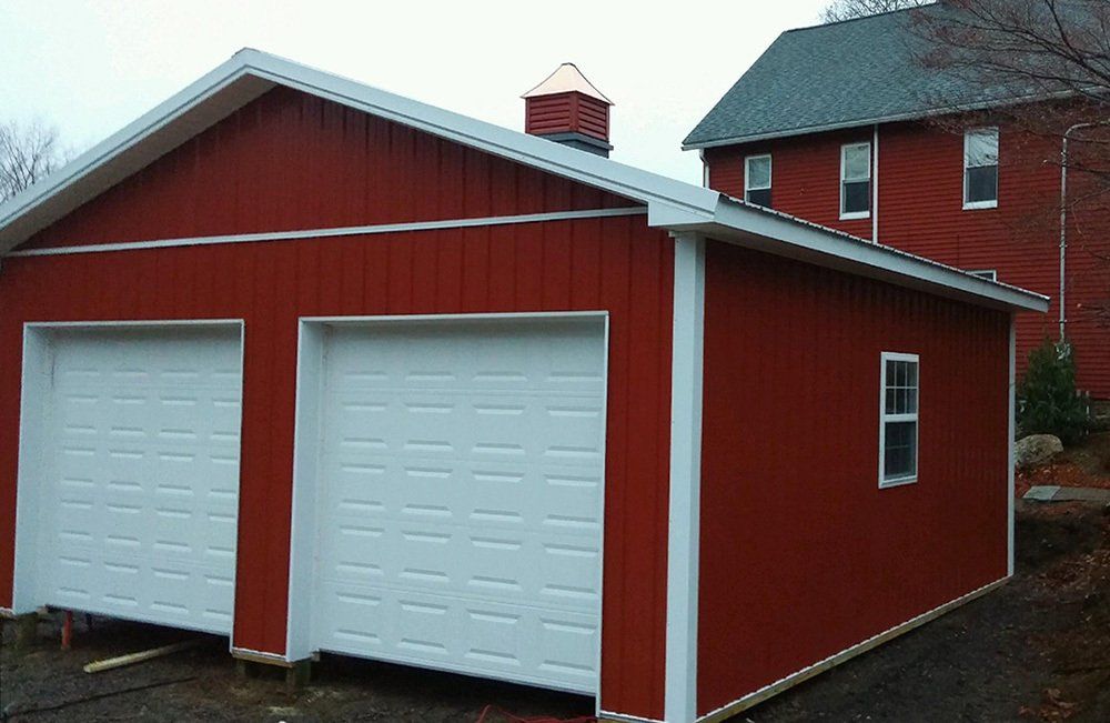 A red garage with white doors is next to a house