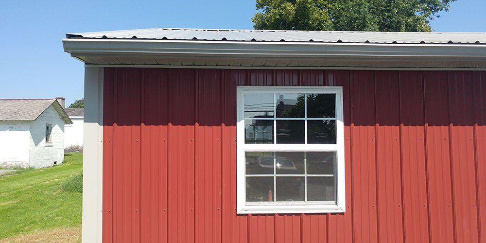 A red barn with a white window on the side of it.