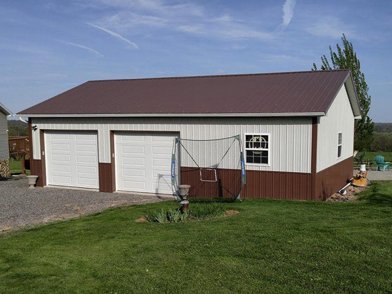A brown and white garage with a swing set in front of it.