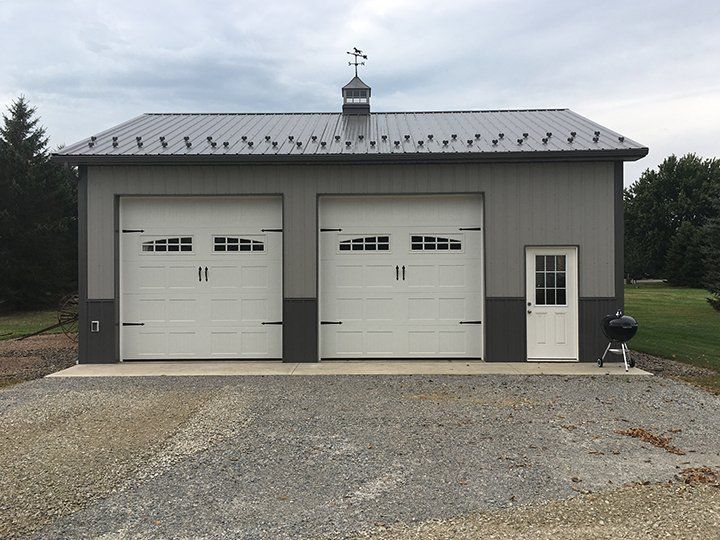 A garage with two white garage doors and a black roof