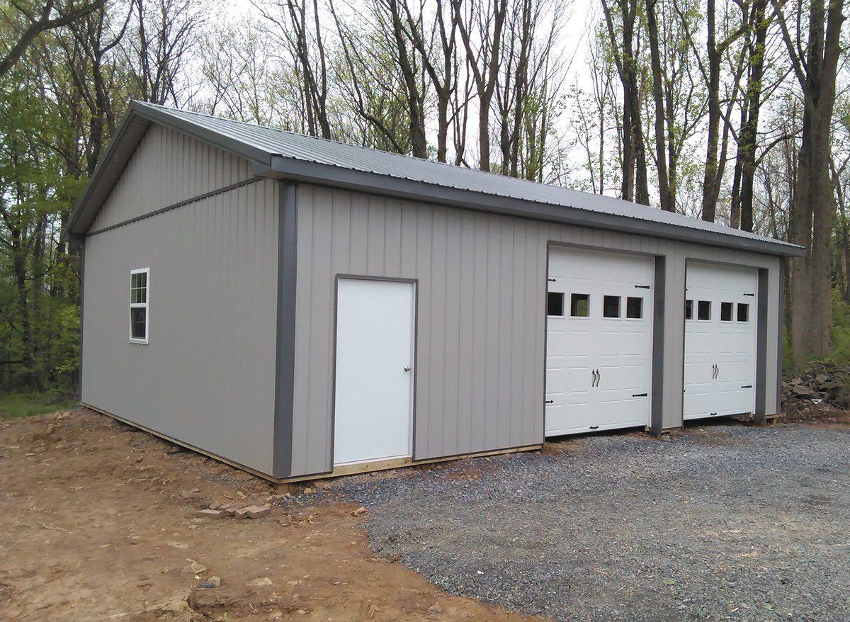 A gray garage with three white garage doors and a window.