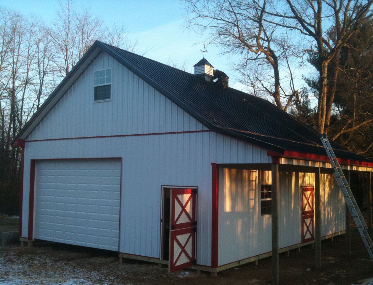A white garage with a black roof and red trim