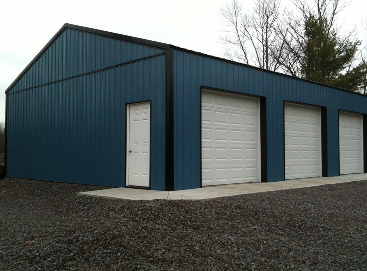 A blue garage with three white garage doors