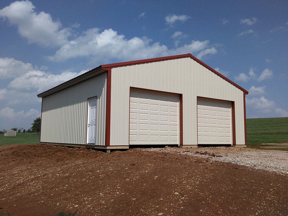 A white building with two garage doors and a red roof