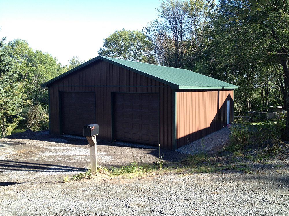 A brown garage with a green roof and a mailbox in front of it