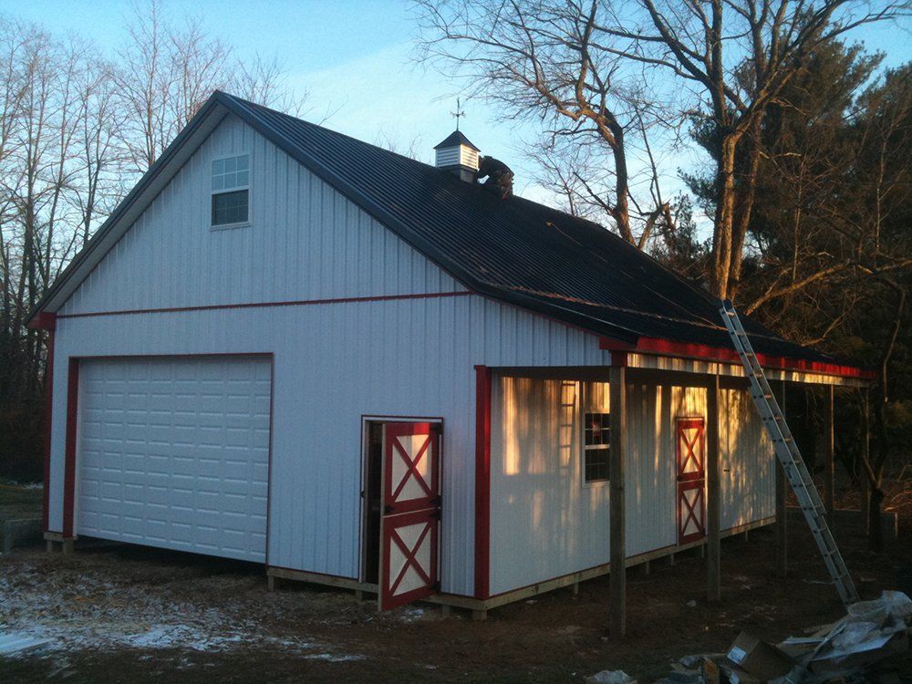 A white barn with red doors and a black roof
