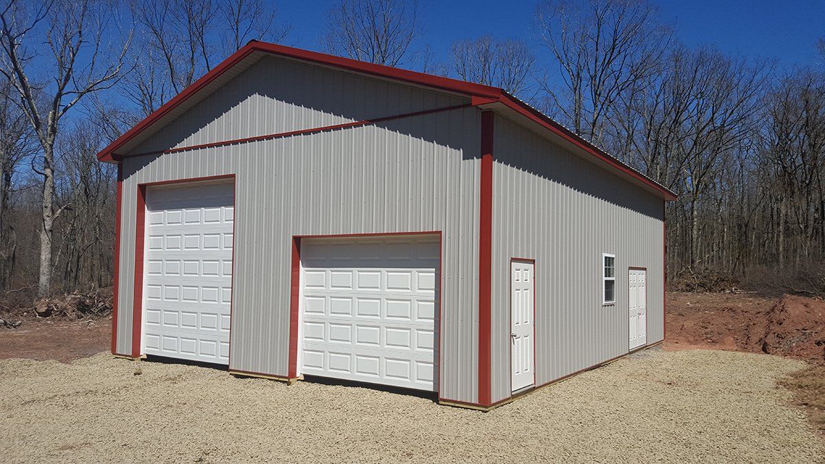A metal garage with two garage doors and a red roof.