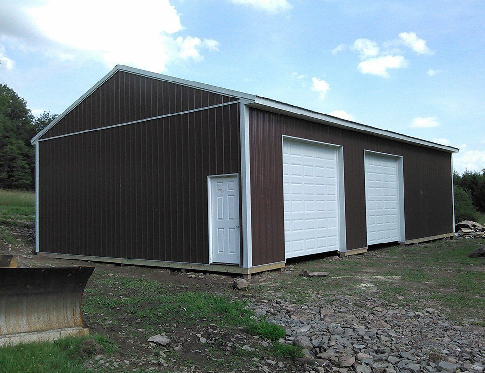 A large brown metal building with white garage doors