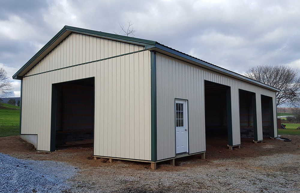A large metal building with a green roof and a white door.