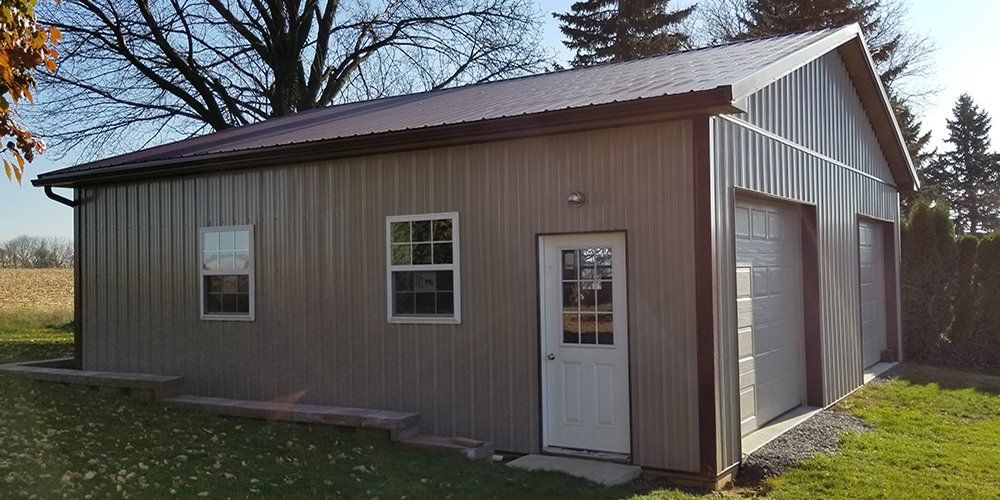 A large metal garage with a brown roof and a white door.