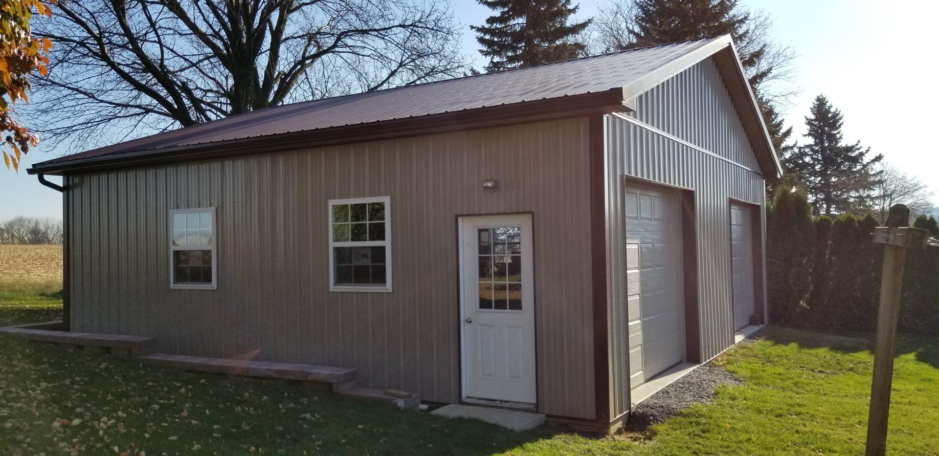 A large metal garage with a brown roof and a white door.